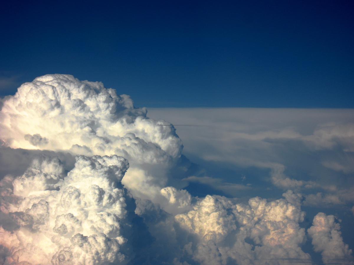 A picturesque view of fluffy clouds and blue sky through an airplane window