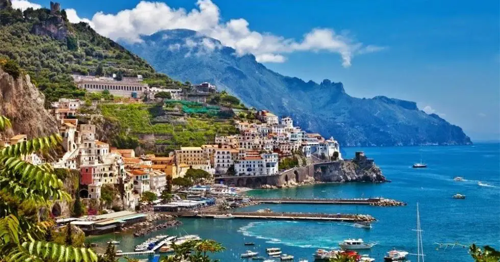 The breathtaking Amalfi Coast in southern Italy, featuring colorful pastel-colored buildings cascading down the cliffs to the sparkling Tyrrhenian Sea.