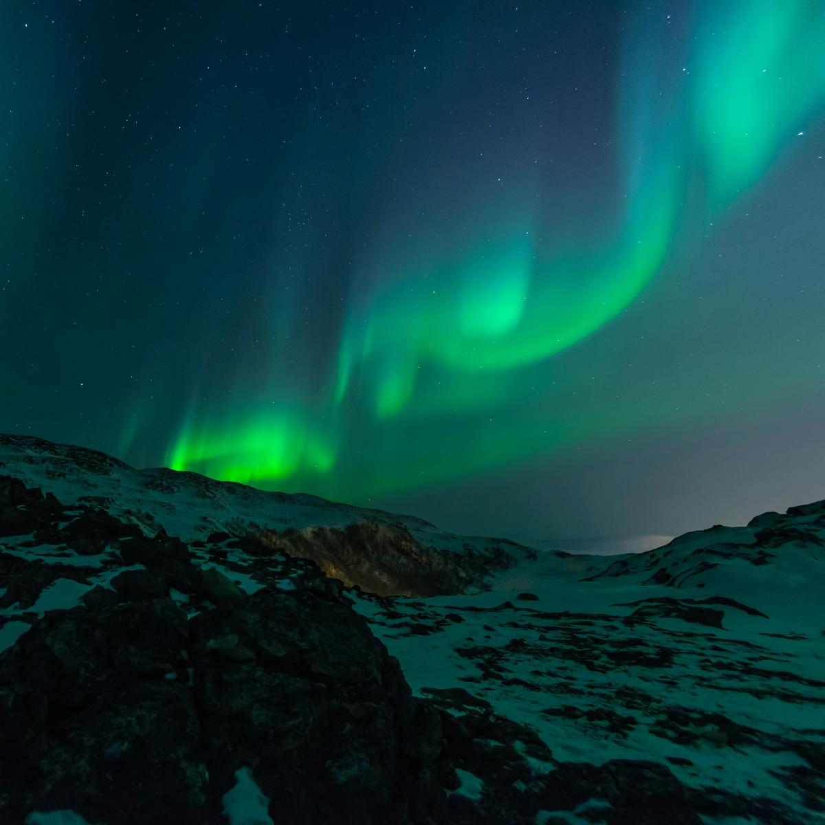 Photograph of vibrant aurora borealis dancing over a northern landscape