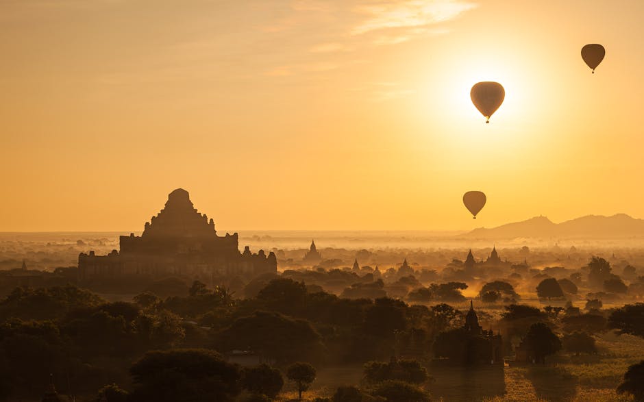 The ancient temples and pagodas of Bagan, Myanmar, dotting the vast plains as hot air balloons float serenely overhead at sunrise.