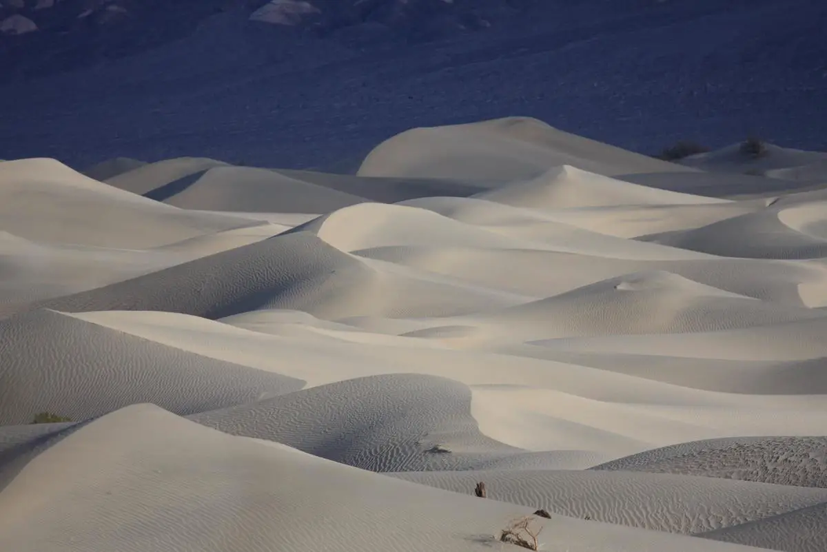 Panoramic view of Furnace Creek in Death Valley, showing rolling dunes, rocky terrain, and a scorching sun