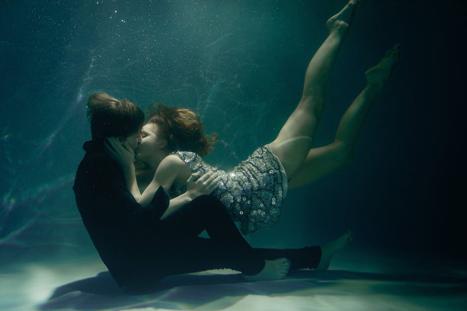 Two figures representing Pisces and Cancer embracing in a serene underwater scene