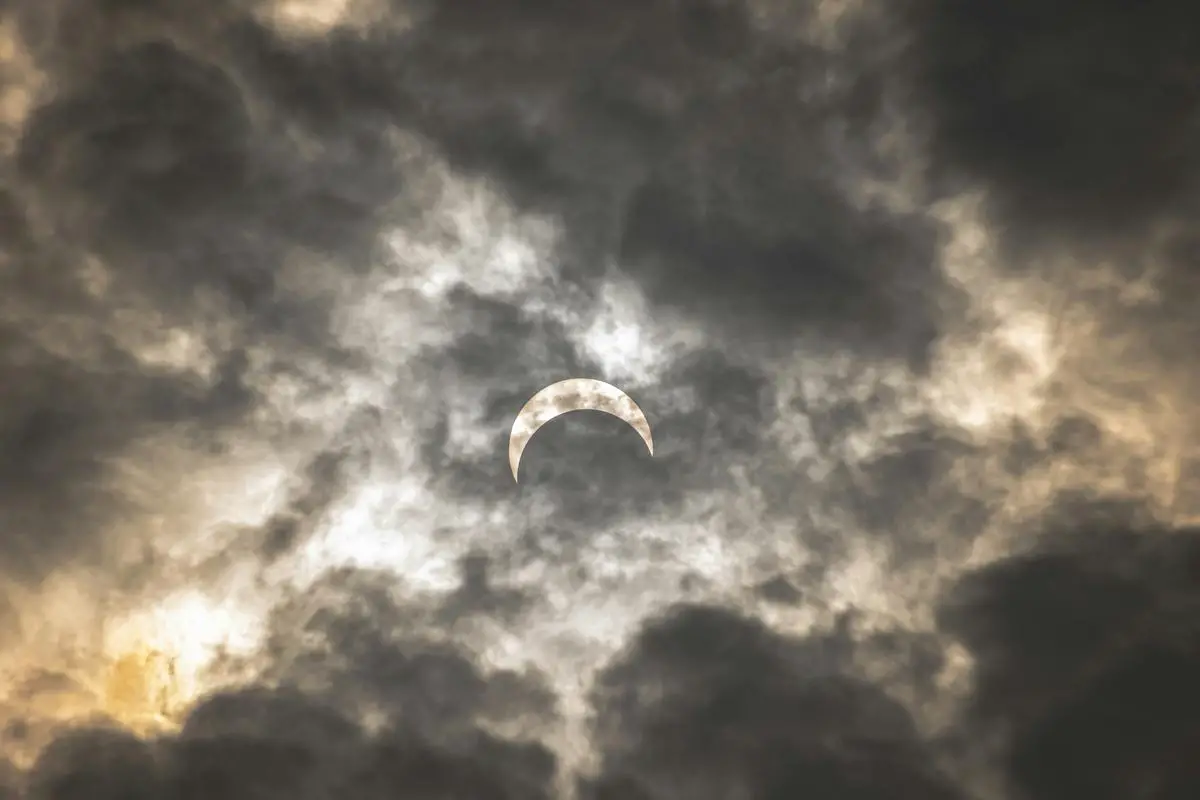 A partial solar eclipse visible over New Zealand's landscape