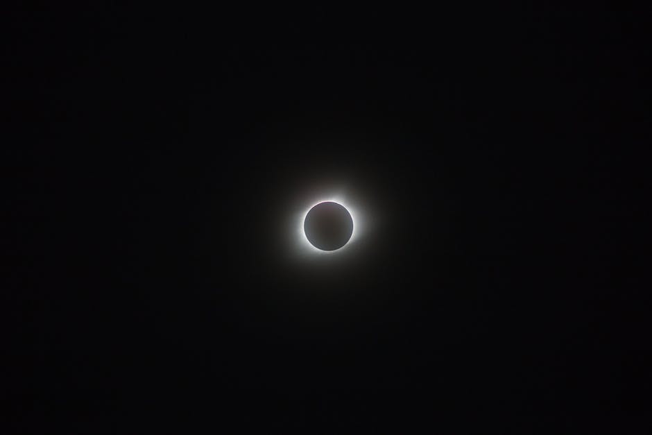 Image of the 2023 solar eclipse showing the moon partially covering the sun, creating a ring of fire, with people observing the phenomenon.