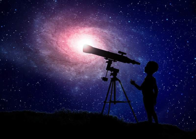 Person using a telescope to observe the Draco constellation in a clear night sky