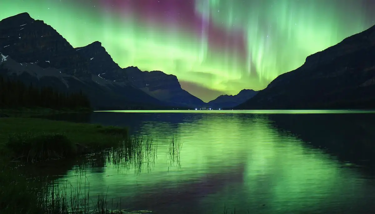 Aurora Borealis over a lake in Waterton-Glacier International Peace Park with mountains in the background